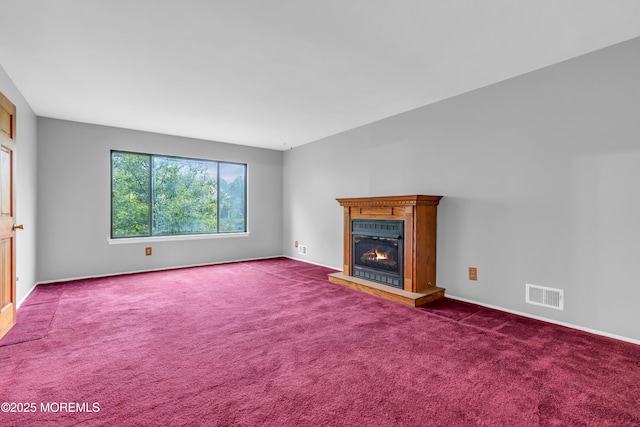 unfurnished living room with dark carpet, a lit fireplace, and baseboards