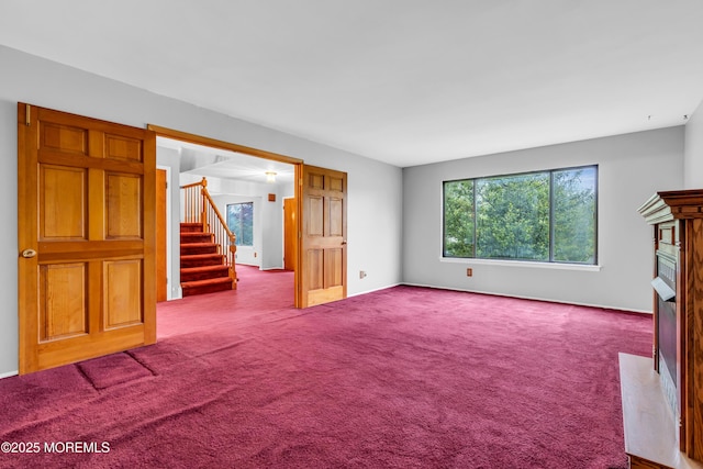 unfurnished living room featuring stairway, a high end fireplace, carpet floors, and baseboards