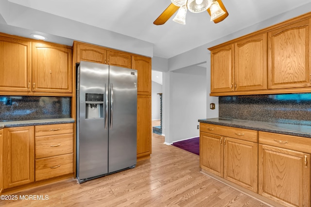 kitchen with stainless steel fridge with ice dispenser, a ceiling fan, backsplash, and dark countertops