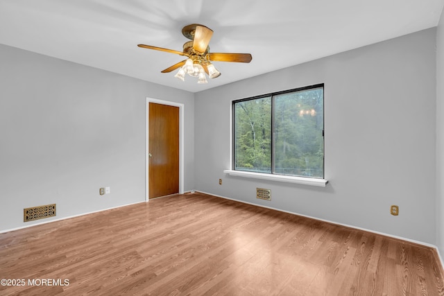 unfurnished room with wood finished floors, a ceiling fan, and baseboards