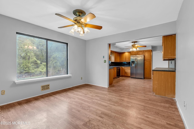 kitchen featuring stainless steel fridge, a ceiling fan, dark countertops, brown cabinetry, and dishwasher