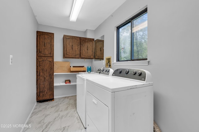 laundry room featuring washing machine and dryer, light marble finish floors, cabinet space, and baseboards