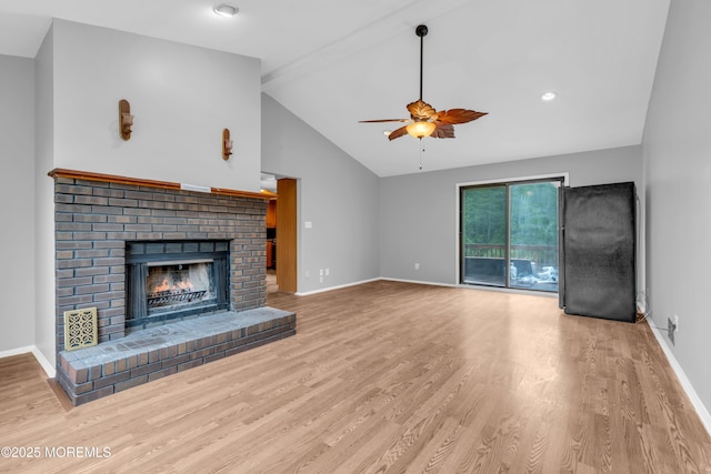 unfurnished living room featuring a ceiling fan, wood finished floors, vaulted ceiling, a fireplace, and baseboards