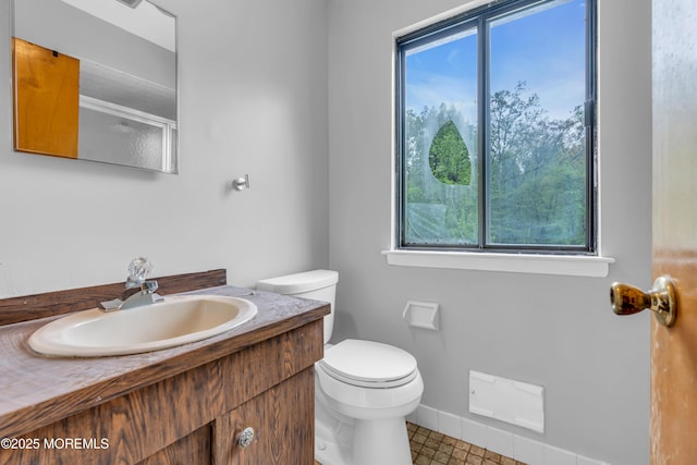 bathroom with plenty of natural light, toilet, vanity, and baseboards