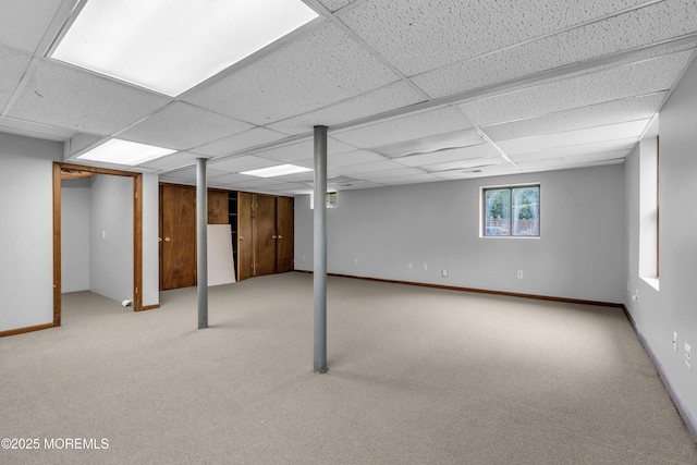below grade area featuring a paneled ceiling, carpet flooring, and baseboards