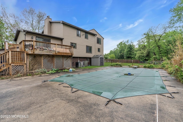 view of pool featuring a deck, a shed, fence, an outbuilding, and a patio