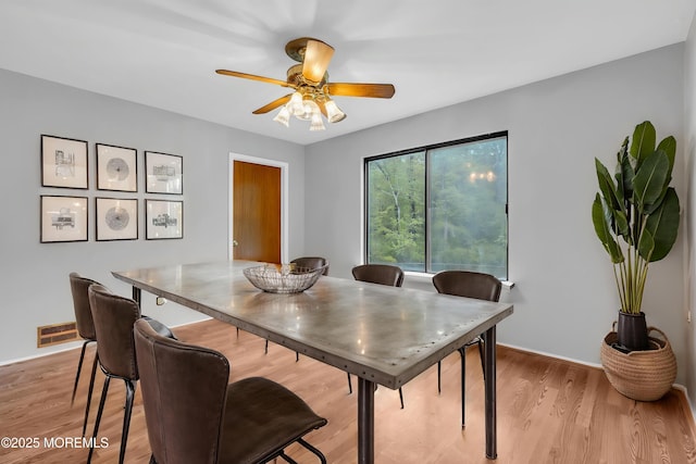 dining room featuring a ceiling fan, light wood finished floors, and baseboards