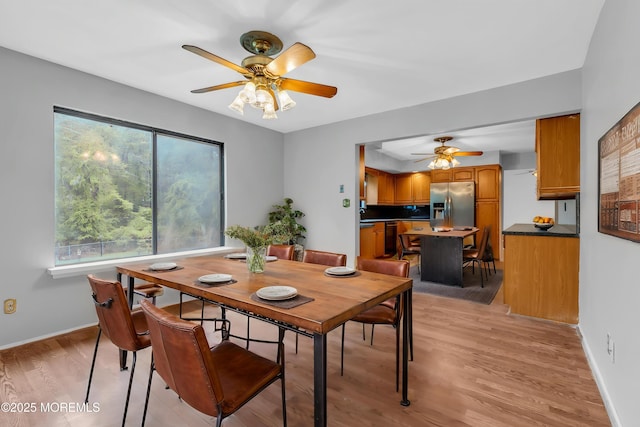 dining room featuring a ceiling fan, light wood-style floors, and baseboards