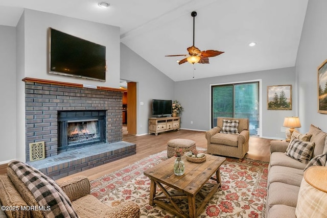living room with wood finished floors, a ceiling fan, baseboards, a fireplace, and high vaulted ceiling