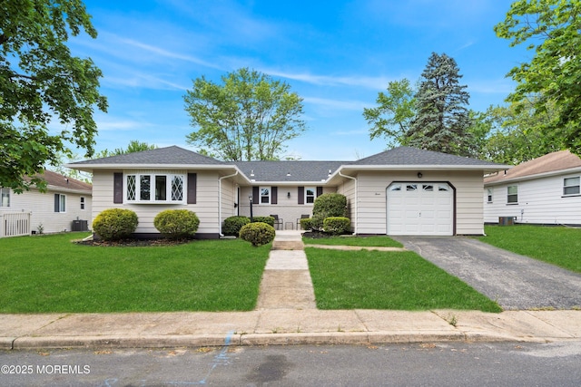 ranch-style home with a garage, asphalt driveway, a front yard, and central AC