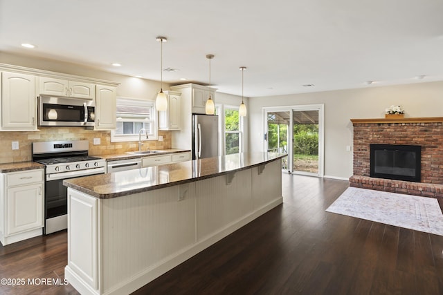kitchen with appliances with stainless steel finishes, a sink, dark wood finished floors, a center island, and recessed lighting