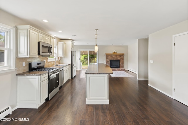 kitchen featuring appliances with stainless steel finishes, a baseboard heating unit, a baseboard radiator, a sink, and a kitchen island