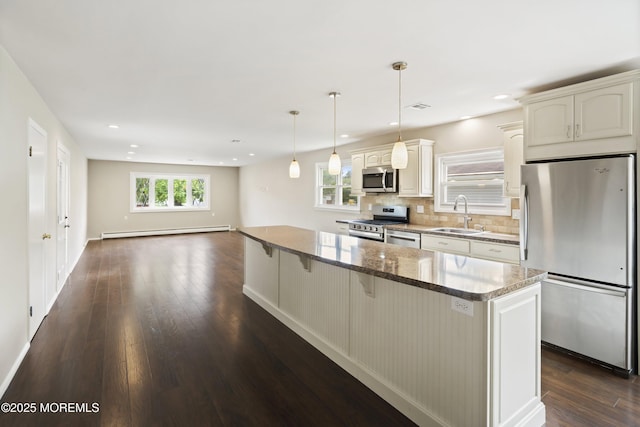 kitchen featuring stainless steel appliances, a sink, dark wood finished floors, a baseboard radiator, and a breakfast bar area