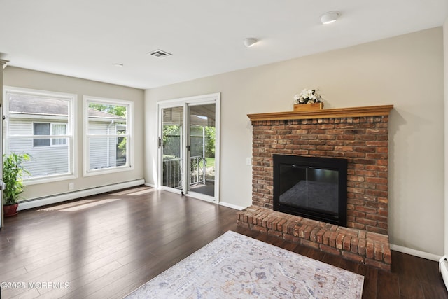 living area with a baseboard heating unit, a brick fireplace, wood-type flooring, and baseboards