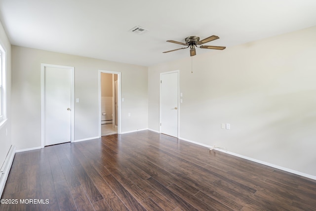 unfurnished bedroom with dark wood finished floors, a baseboard heating unit, baseboards, and a ceiling fan