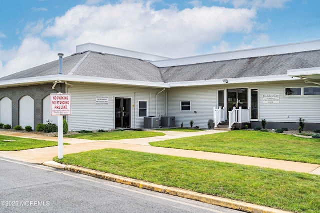 view of front of property featuring a front lawn, central air condition unit, and a shingled roof