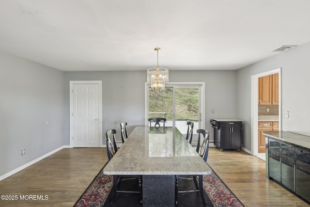 dining room featuring a chandelier, wood finished floors, and baseboards