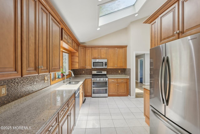 kitchen featuring appliances with stainless steel finishes, a skylight, a sink, light stone countertops, and light tile patterned floors