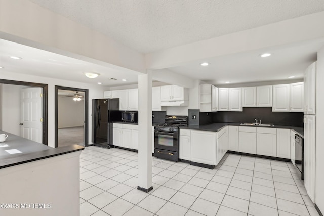 kitchen featuring black appliances, a sink, dark countertops, under cabinet range hood, and white cabinets
