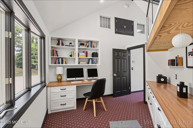 office featuring built in study area, dark carpet, high vaulted ceiling, and baseboards