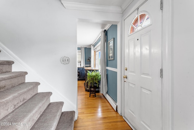 entryway with ornamental molding, light wood-style floors, healthy amount of natural light, stairs, and a baseboard heating unit