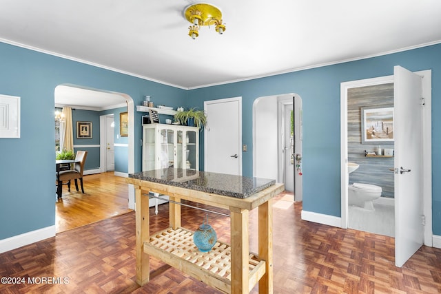 kitchen featuring arched walkways, baseboards, and crown molding