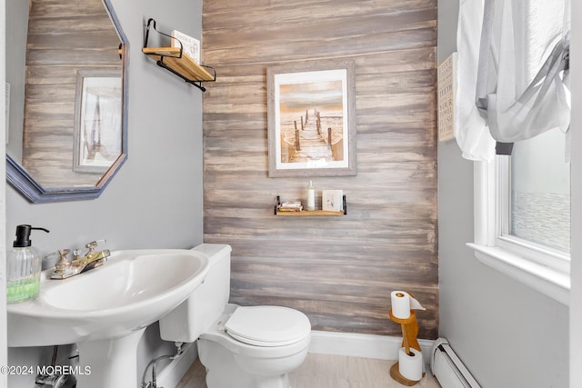 bathroom featuring toilet, a baseboard heating unit, and a sink