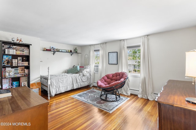 bedroom featuring wood finished floors and a baseboard heating unit