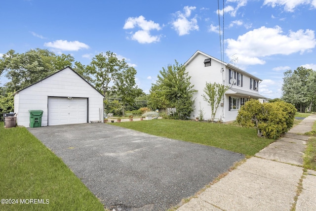view of home's exterior featuring a garage, an outdoor structure, a lawn, and driveway