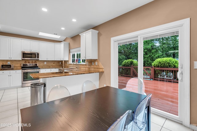352 Meadowood Rd, Jackson, NJ 08527 - kitchen with stainless steel appliances, light tile patterned floors, white cabinets, a skylight, and decorative backsplash