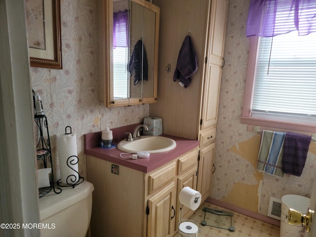 bathroom with vanity, toilet, and wallpapered walls