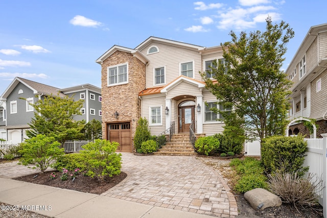 view of front facade with fence, stone siding, a garage, and decorative driveway