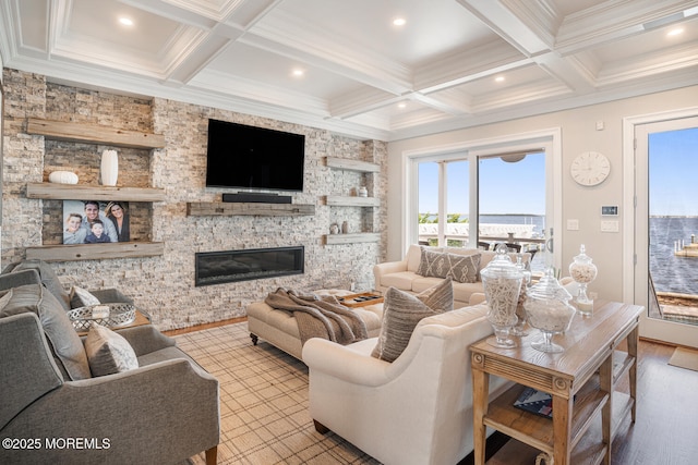 living room featuring coffered ceiling, beamed ceiling, wood finished floors, crown molding, and a stone fireplace