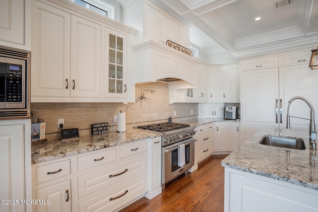 kitchen featuring appliances with stainless steel finishes, a sink, wood finished floors, tasteful backsplash, and ornamental molding