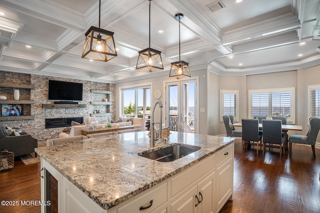 kitchen featuring a sink, healthy amount of natural light, coffered ceiling, open floor plan, and crown molding