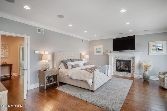 bedroom featuring recessed lighting, wood finished floors, ornamental molding, a tile fireplace, and baseboards