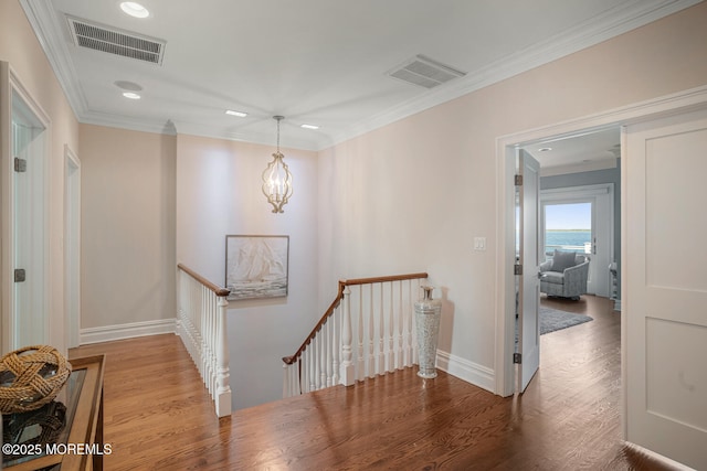 hall with an upstairs landing, wood finished floors, recessed lighting, baseboards, and crown molding