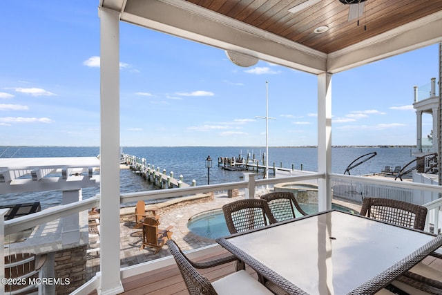 wooden terrace with a water view, a boat dock, boat lift, and outdoor dining area