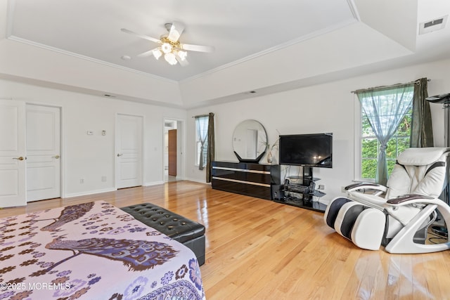 bedroom featuring wood finished floors, a raised ceiling, ornamental molding, and ceiling fan
