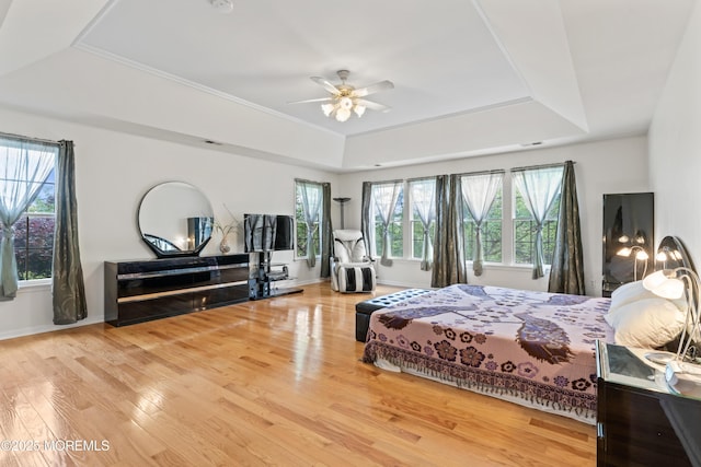 bedroom featuring a tray ceiling, wood finished floors, baseboards, and ceiling fan