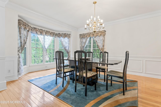 dining room with a chandelier, healthy amount of natural light, light wood-style flooring, crown molding, and wainscoting