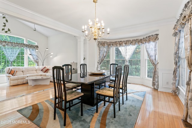 dining area featuring healthy amount of natural light, a chandelier, light wood-type flooring, decorative columns, and crown molding