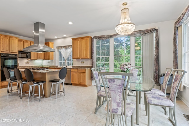 kitchen with island exhaust hood, black appliances, a center island, a kitchen bar, and a chandelier