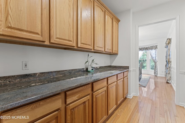 kitchen with light wood-style flooring and dark stone counters