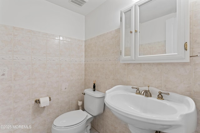 bathroom with tile walls, toilet, and a sink