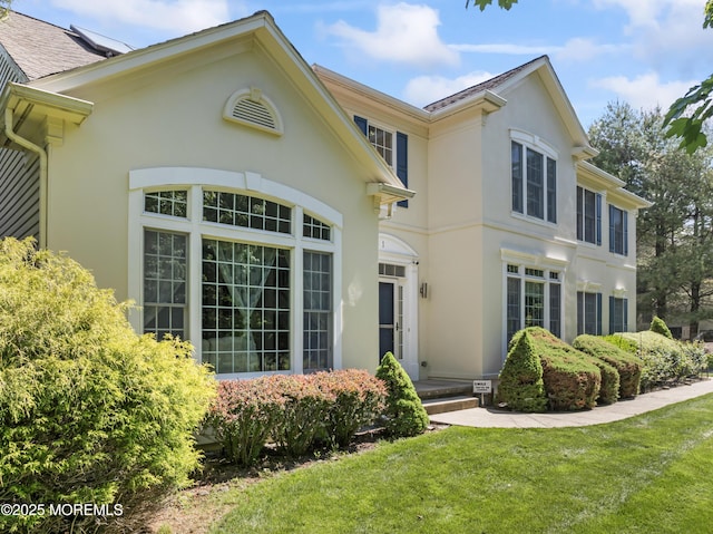 back of property with stucco siding and a yard