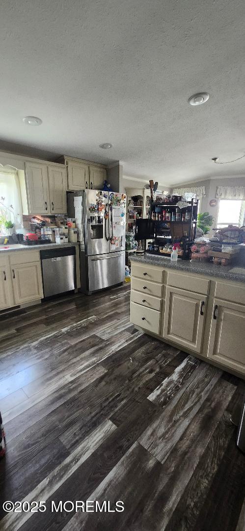 kitchen with stainless steel appliances, dark wood-style floors, and a textured ceiling