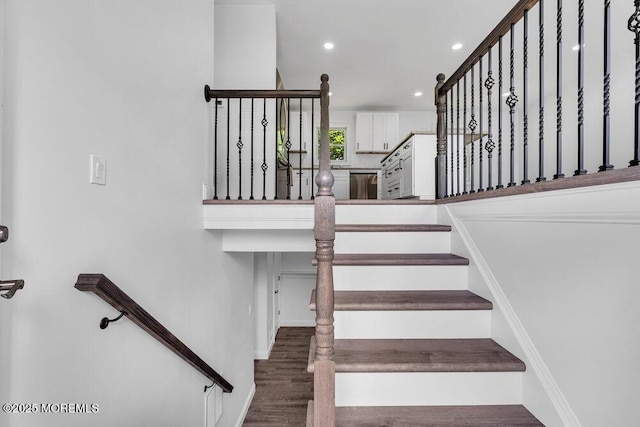 stairs with wood finished floors and recessed lighting