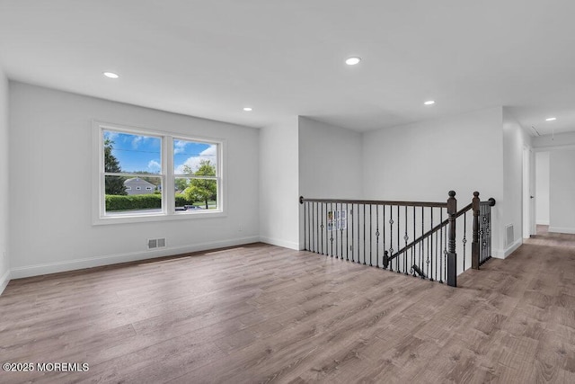 spare room with attic access, recessed lighting, wood finished floors, and baseboards