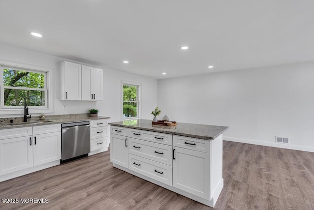 kitchen with dishwasher, a sink, healthy amount of natural light, stone countertops, and recessed lighting